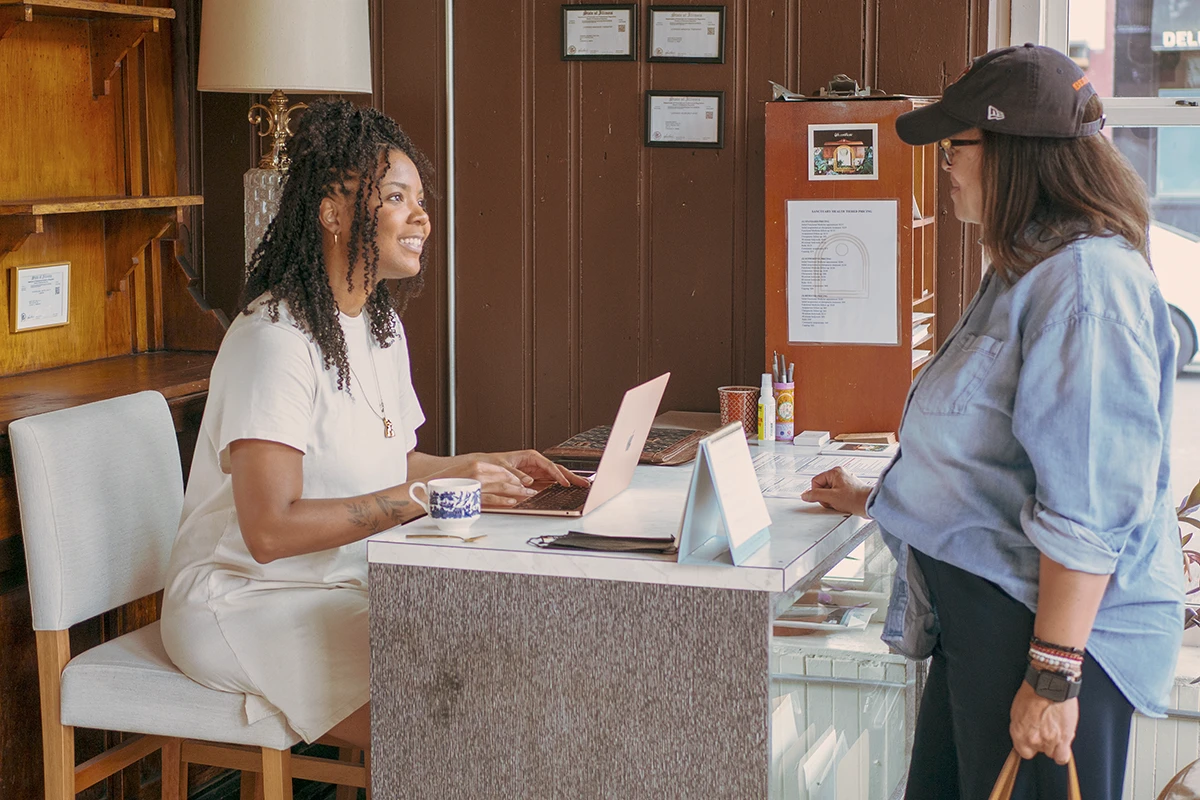 Sanctuary Health practitioner smiling and speaking with a patient at the front desk in Chicago.